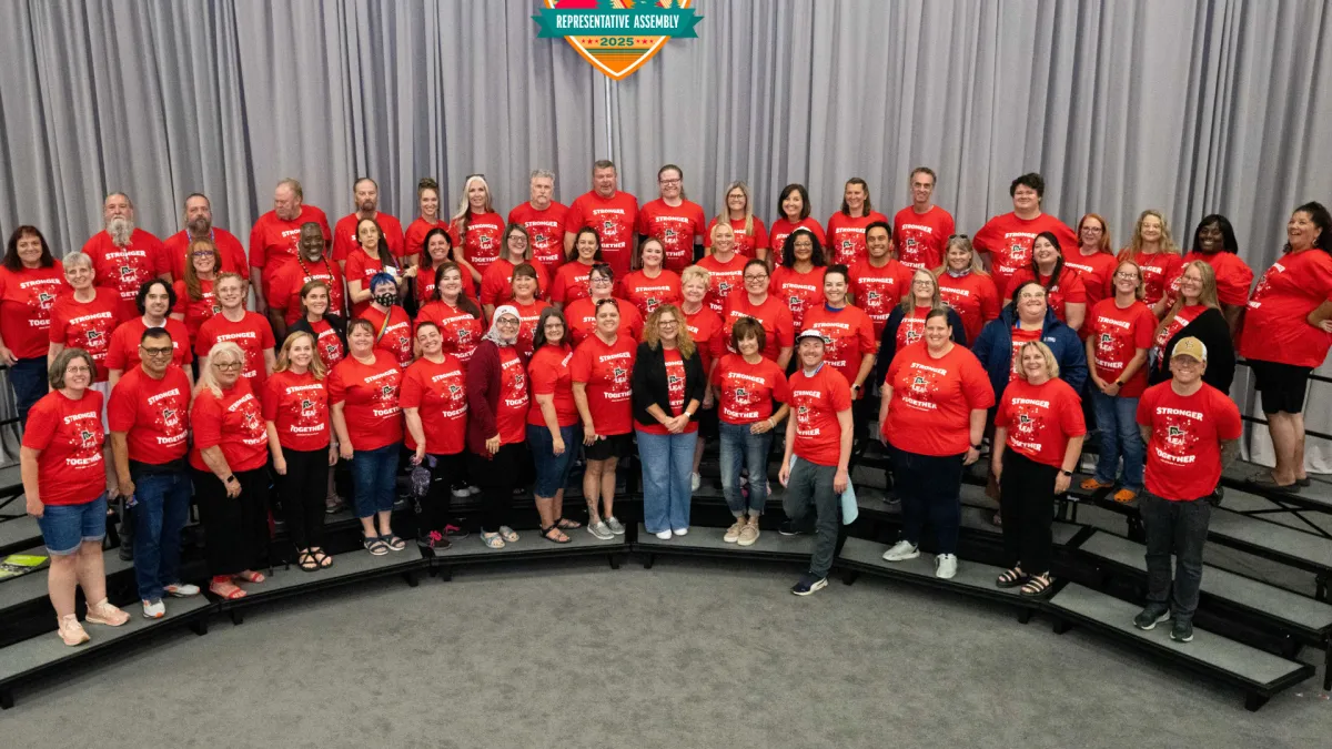 Group of educators wearing red smile at the camera.