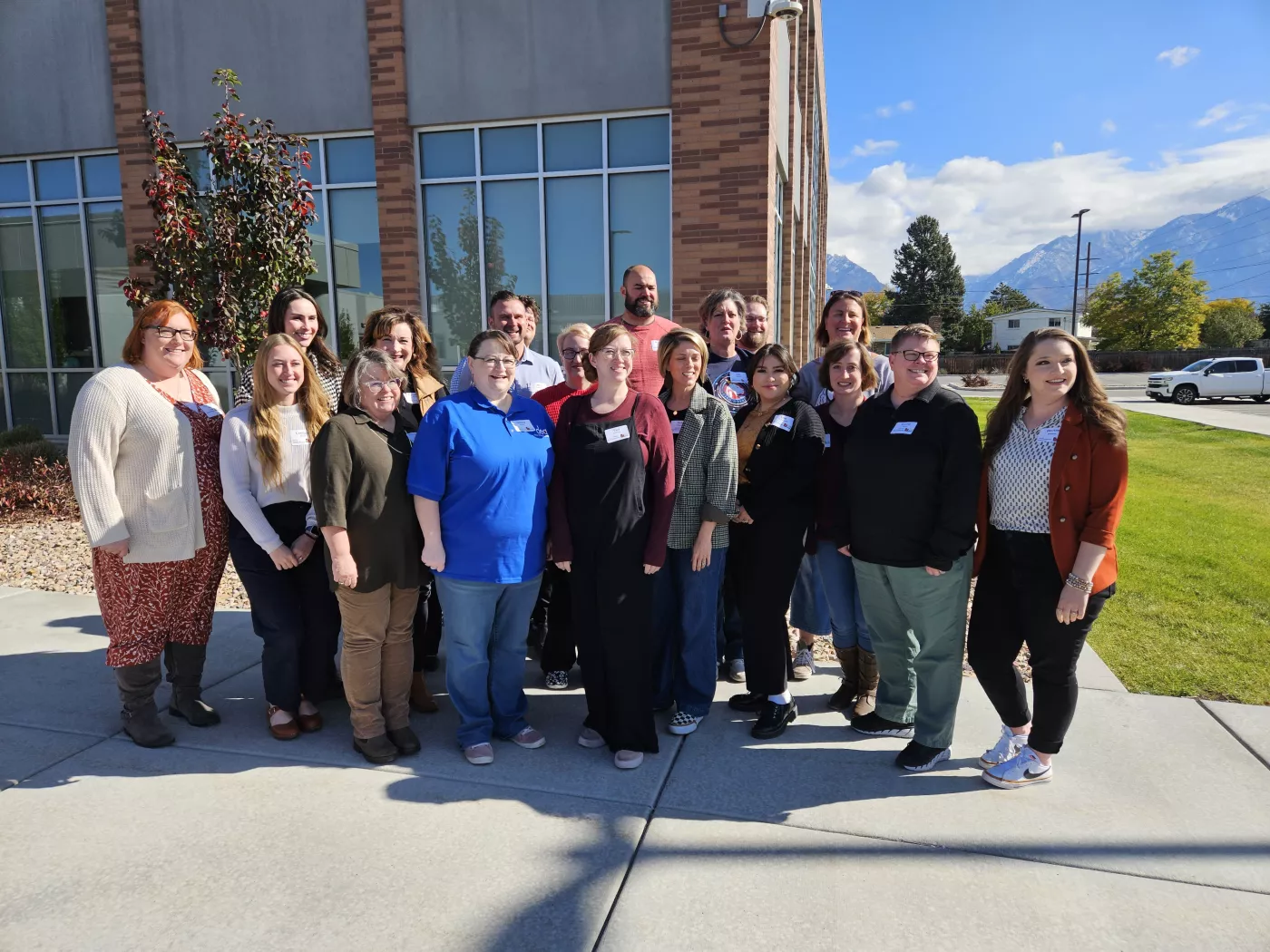 A group of educators standing outside smiling with a building in the background.
