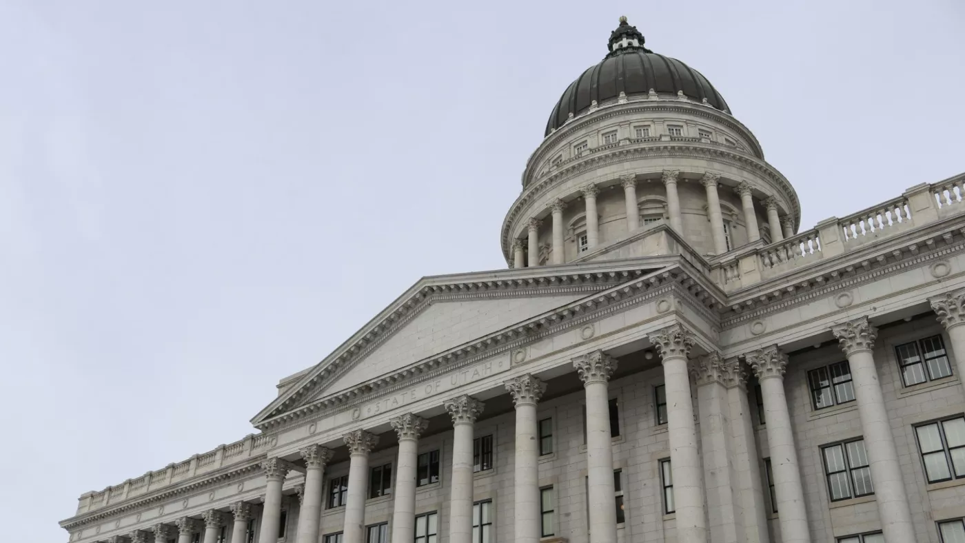 The dome and entrance of the Utah capitol against a grey sky.