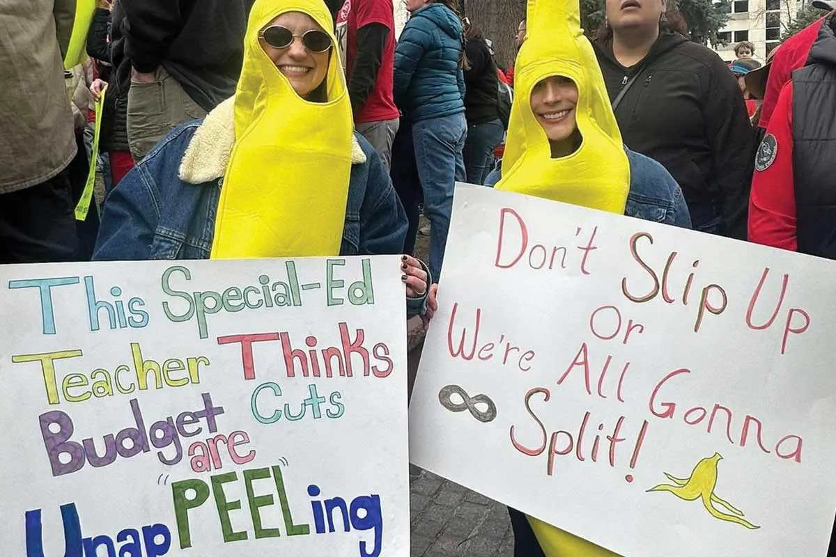 Two female protesters wearing banana costumes with various signs.
