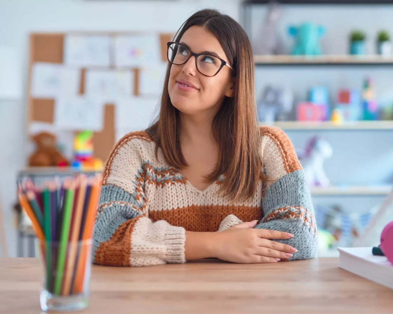 An educator sits at their desk looking up thoughtfully