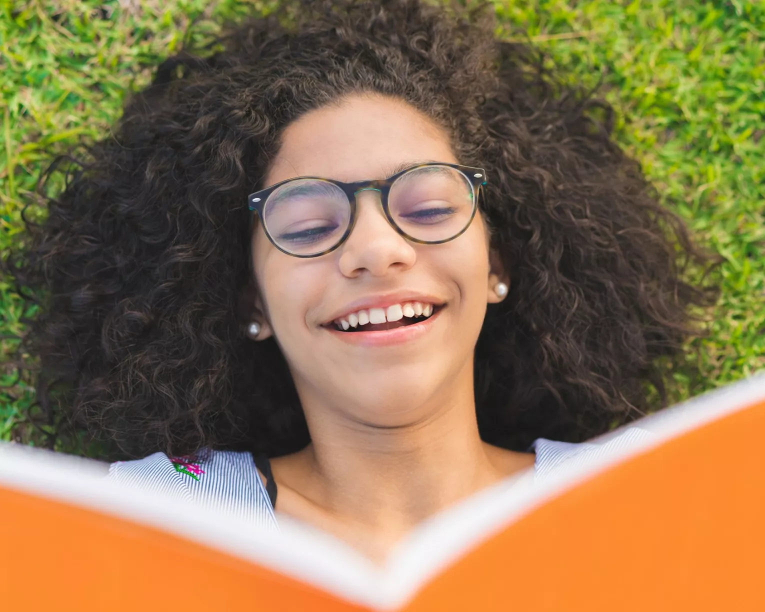 girl lying on the grass and reading a book