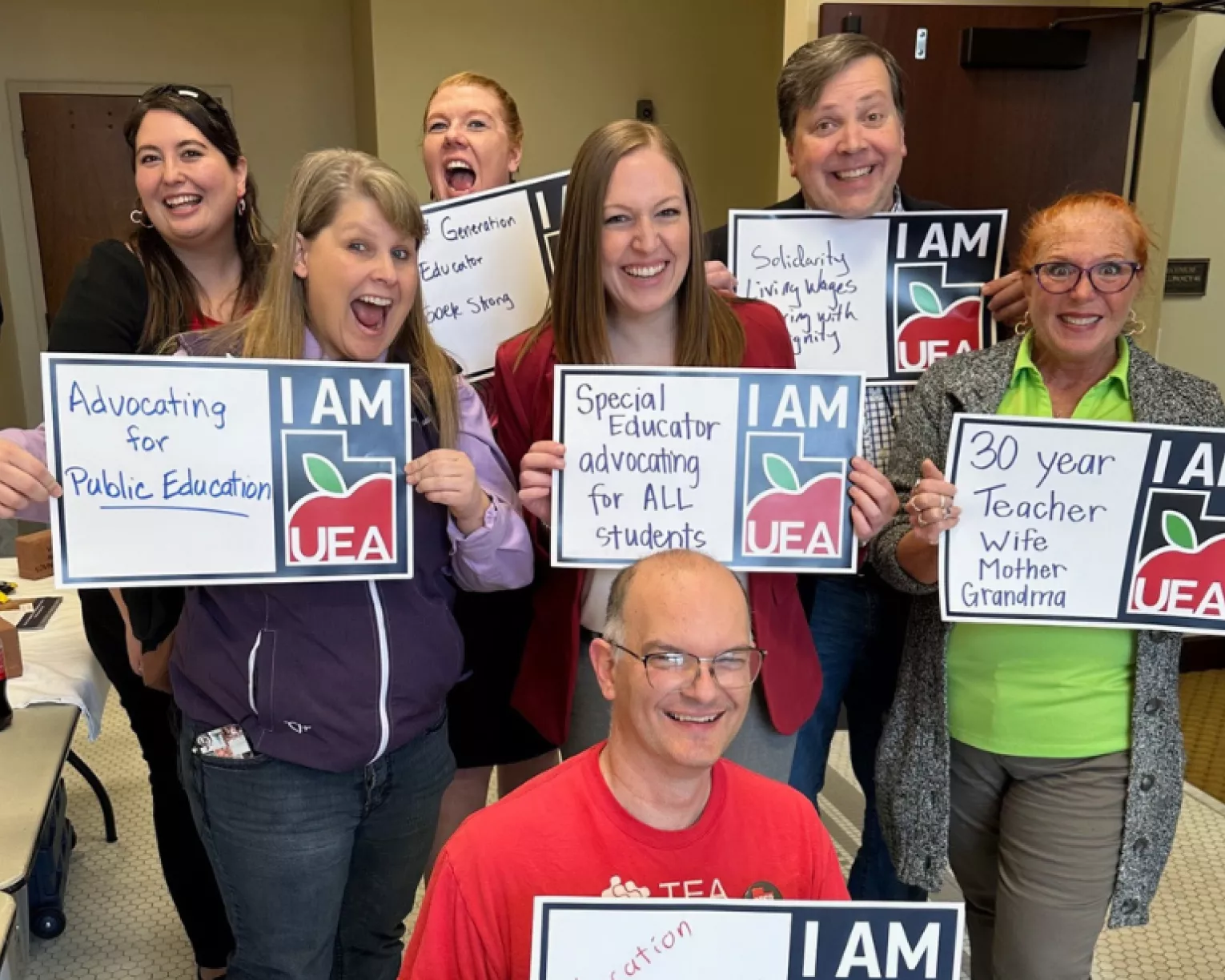 Seven people hold up signs that read: I am UEA.