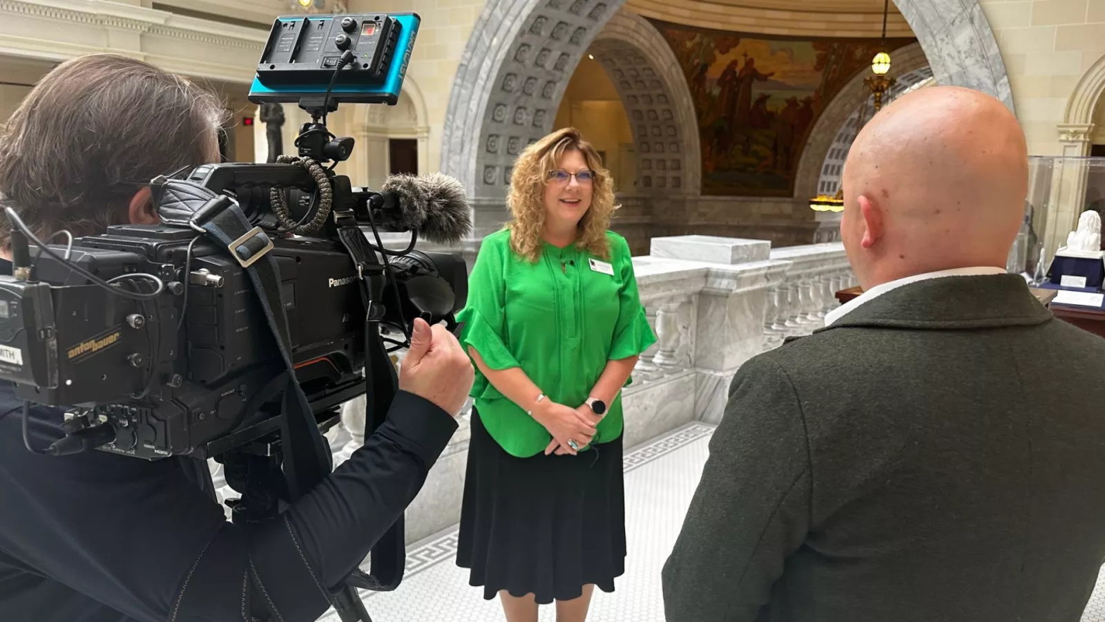 Renee Pinkney interviewed by news media wearing green shirt. 