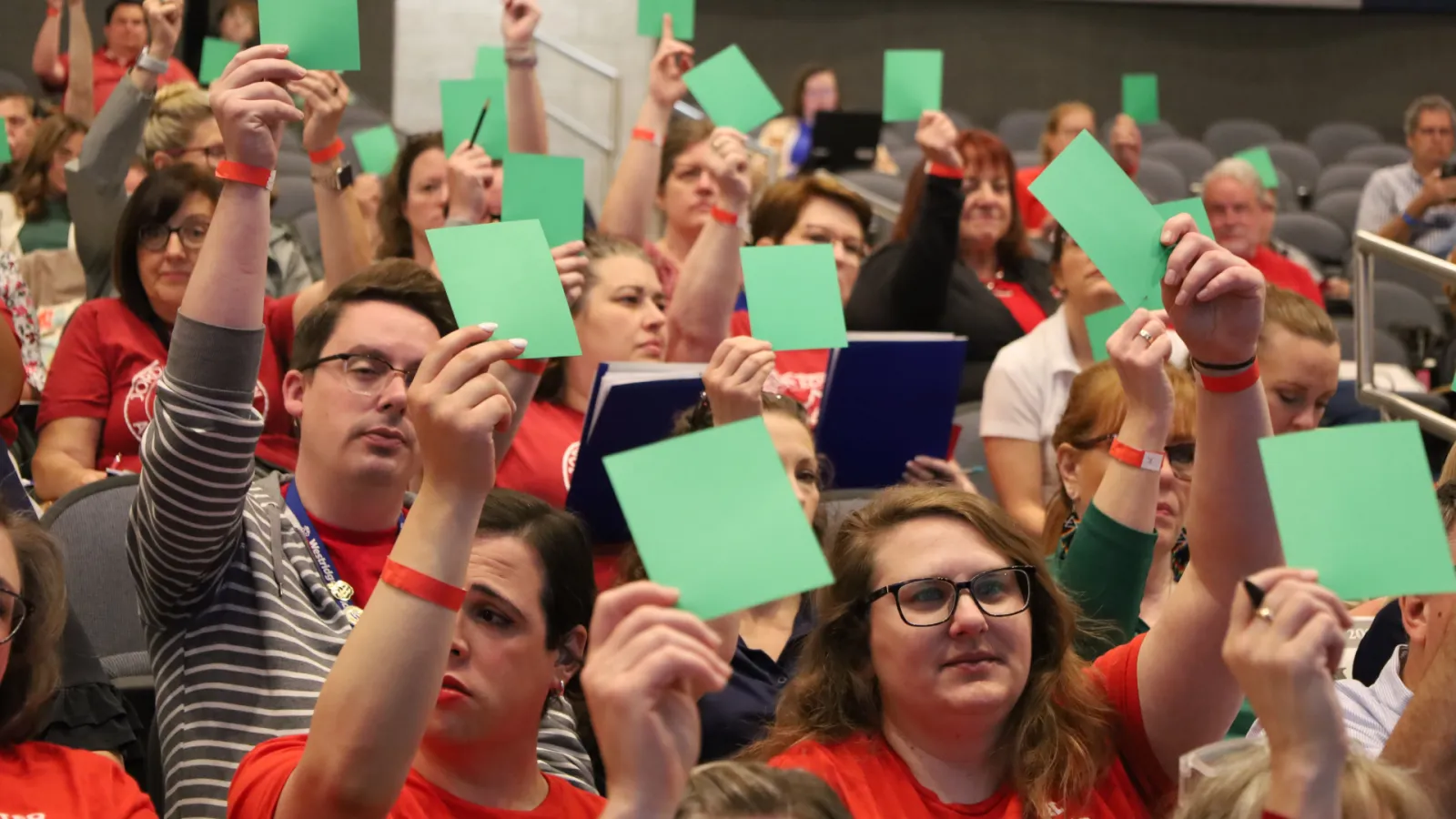Group holding up green cards while voting at HOD. 