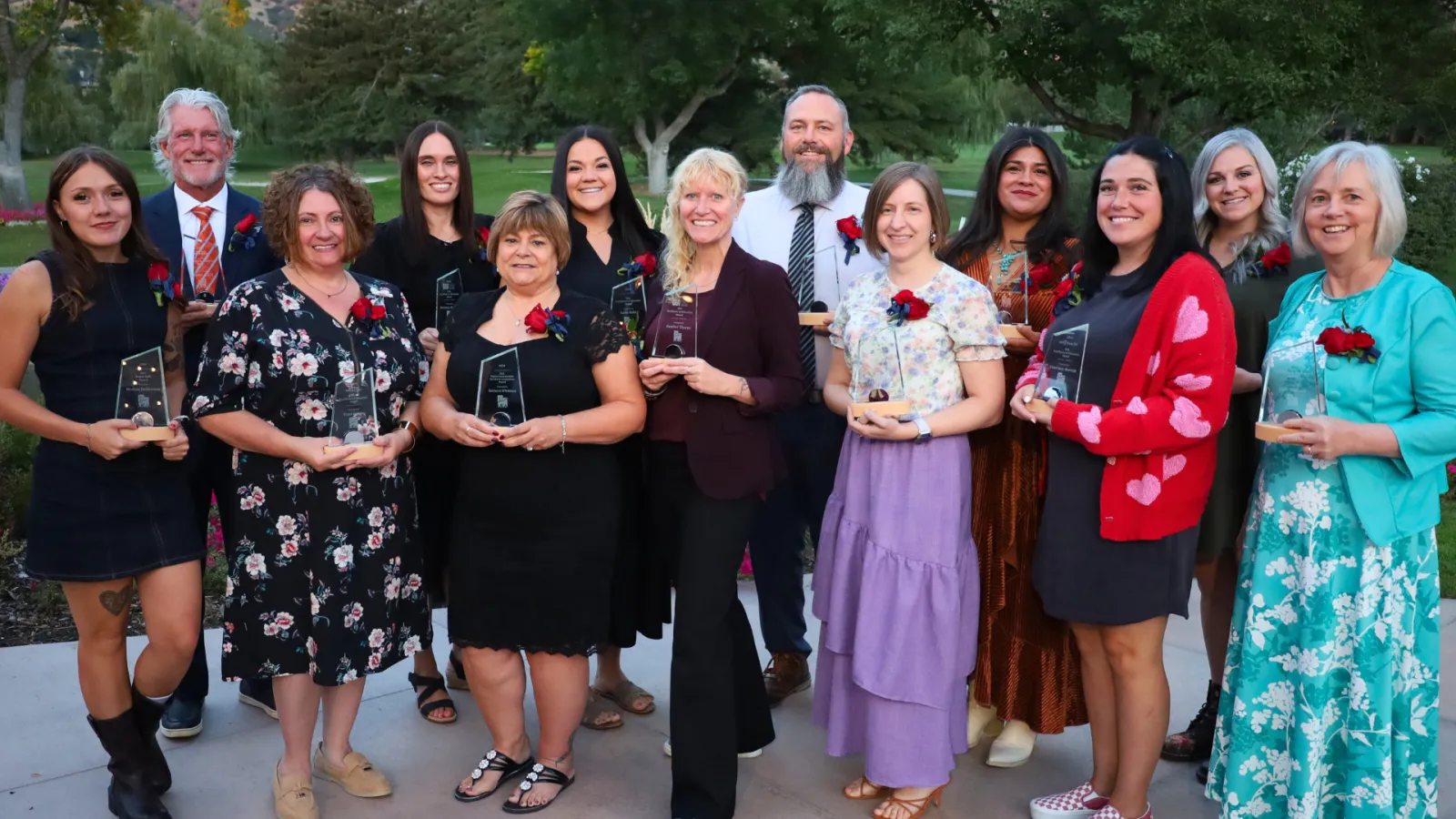 Group of people smile holding trophies. 