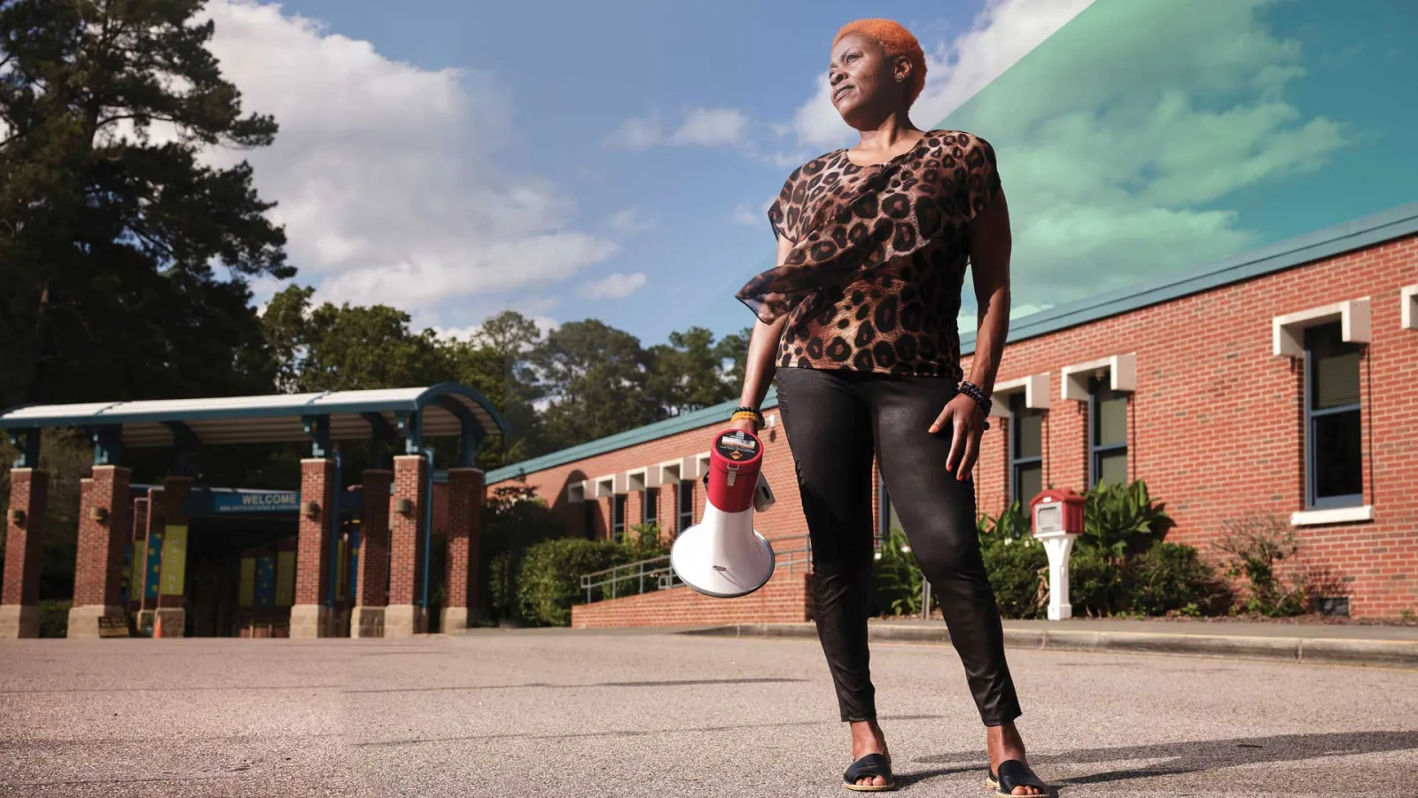 NCAE head custodian Patricia Crews outside of a school holding a bullhorn.