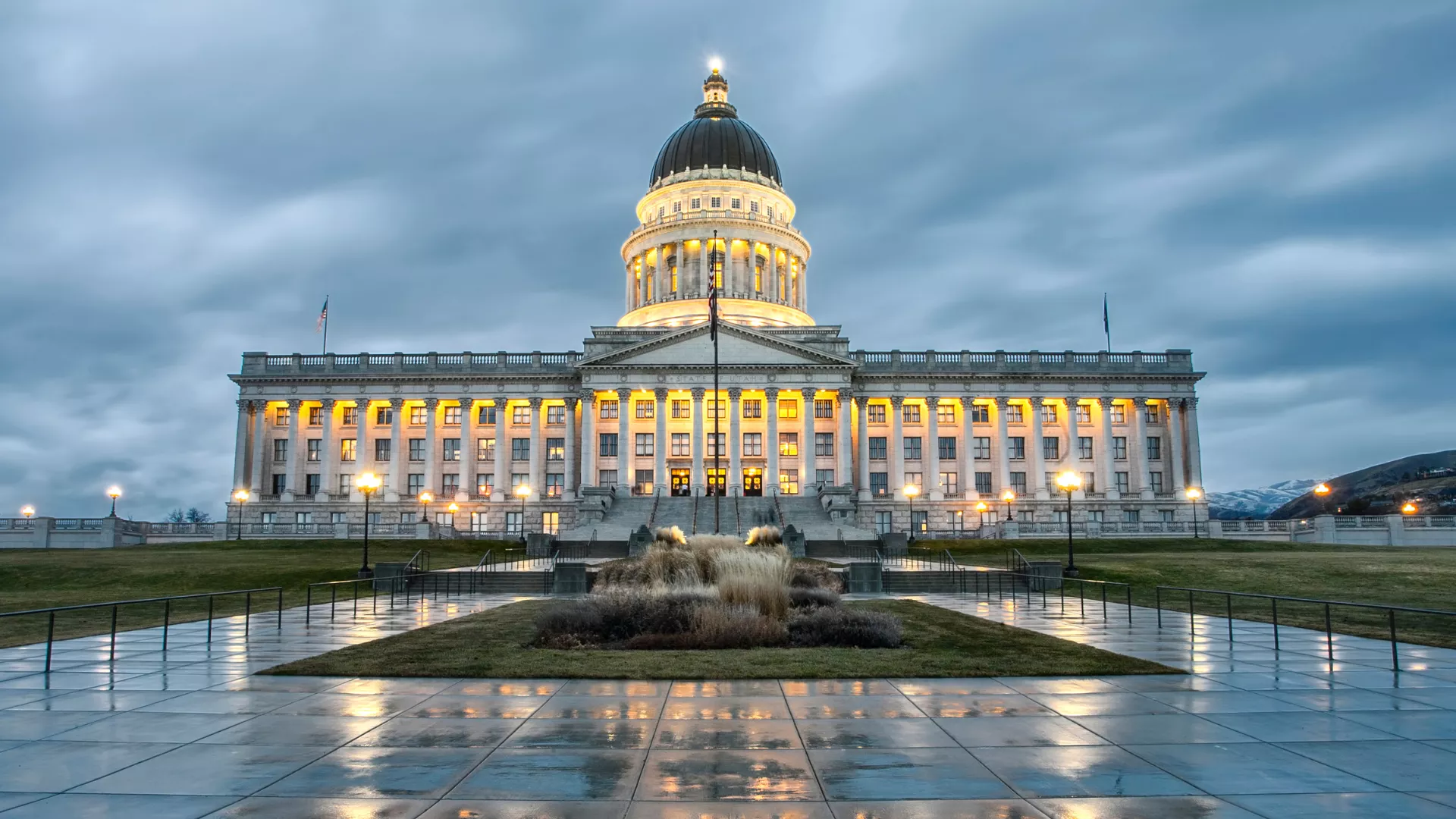Utah's capitol building on a cloudy evening with wet pavement reflecting the building's lights.