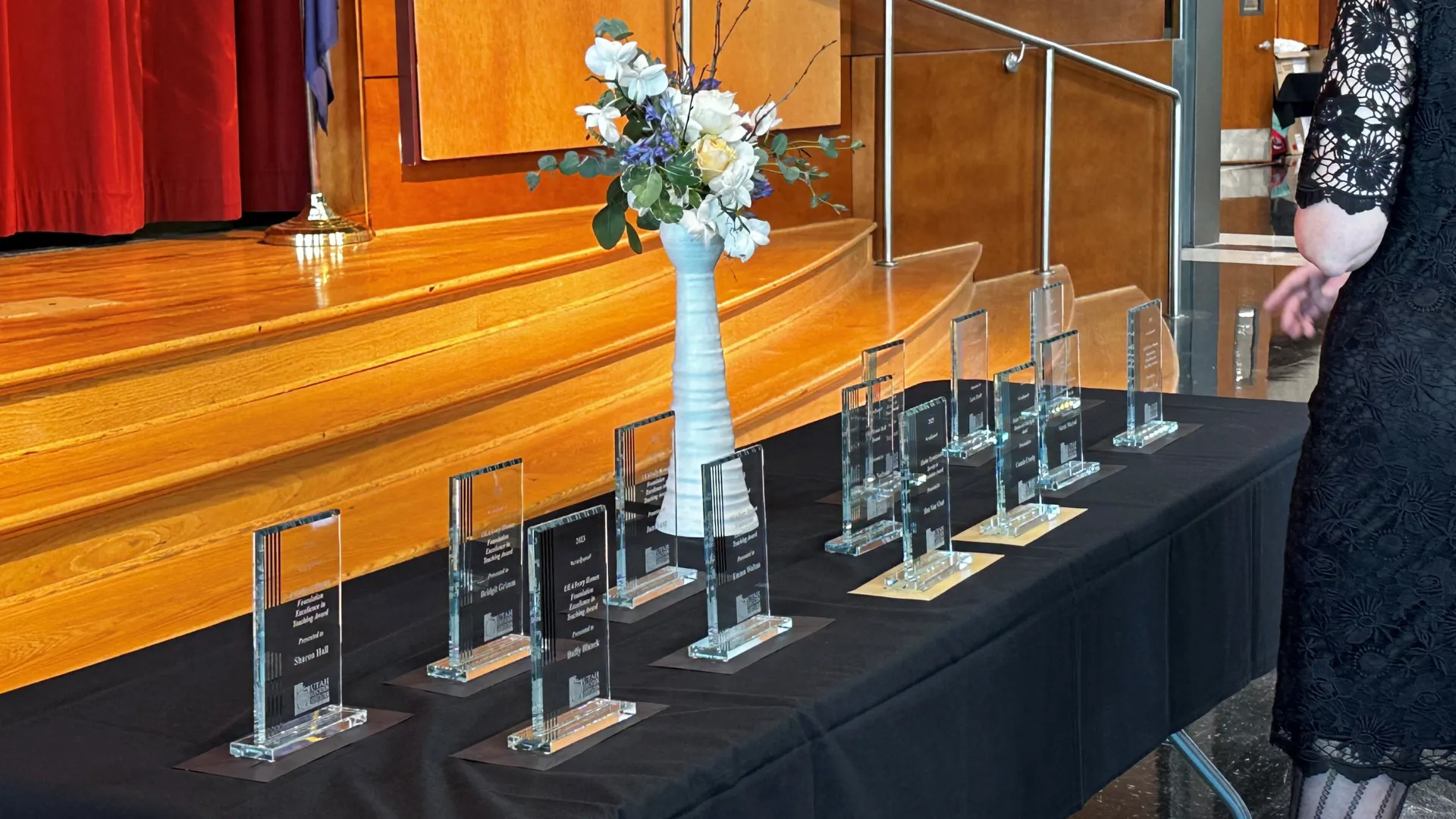 Row of glass trophies on a table with flowers.
