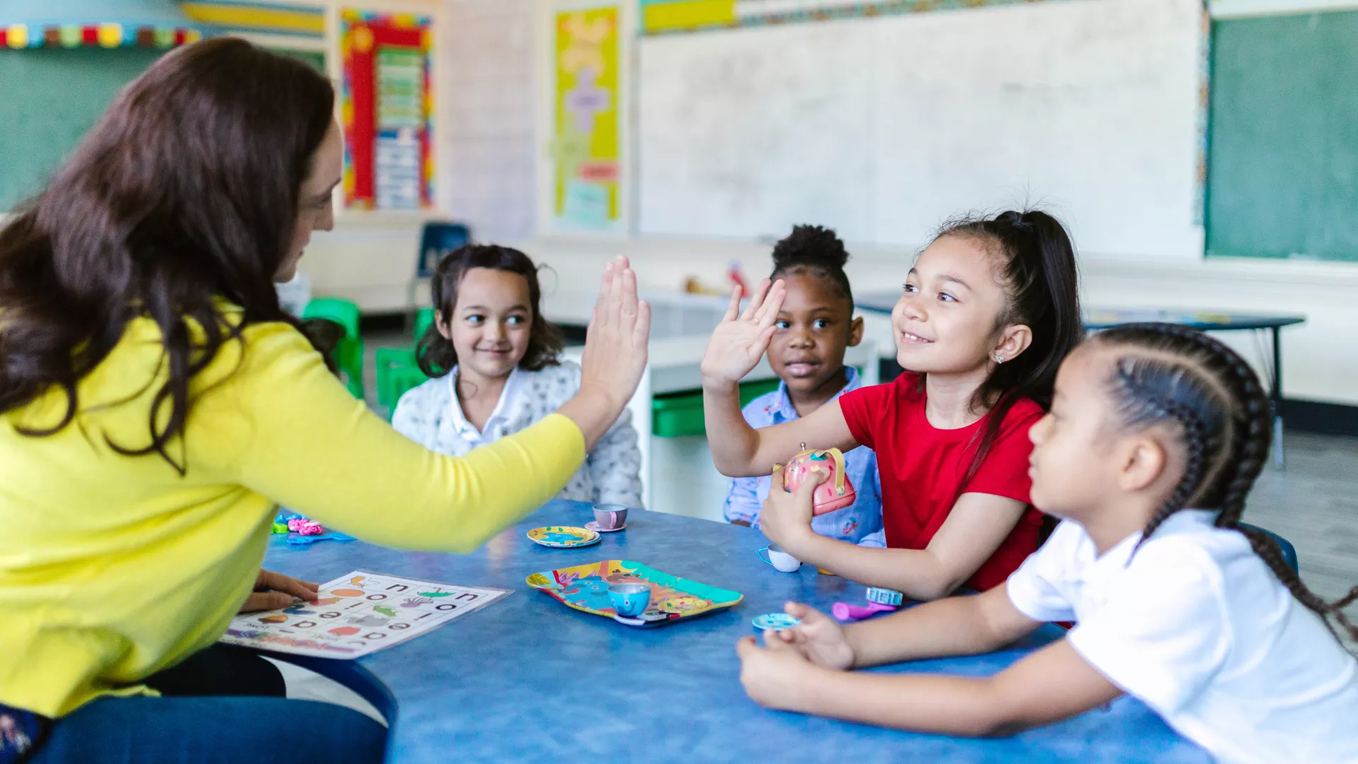 Teacher in yellow sweater high-fives a student.