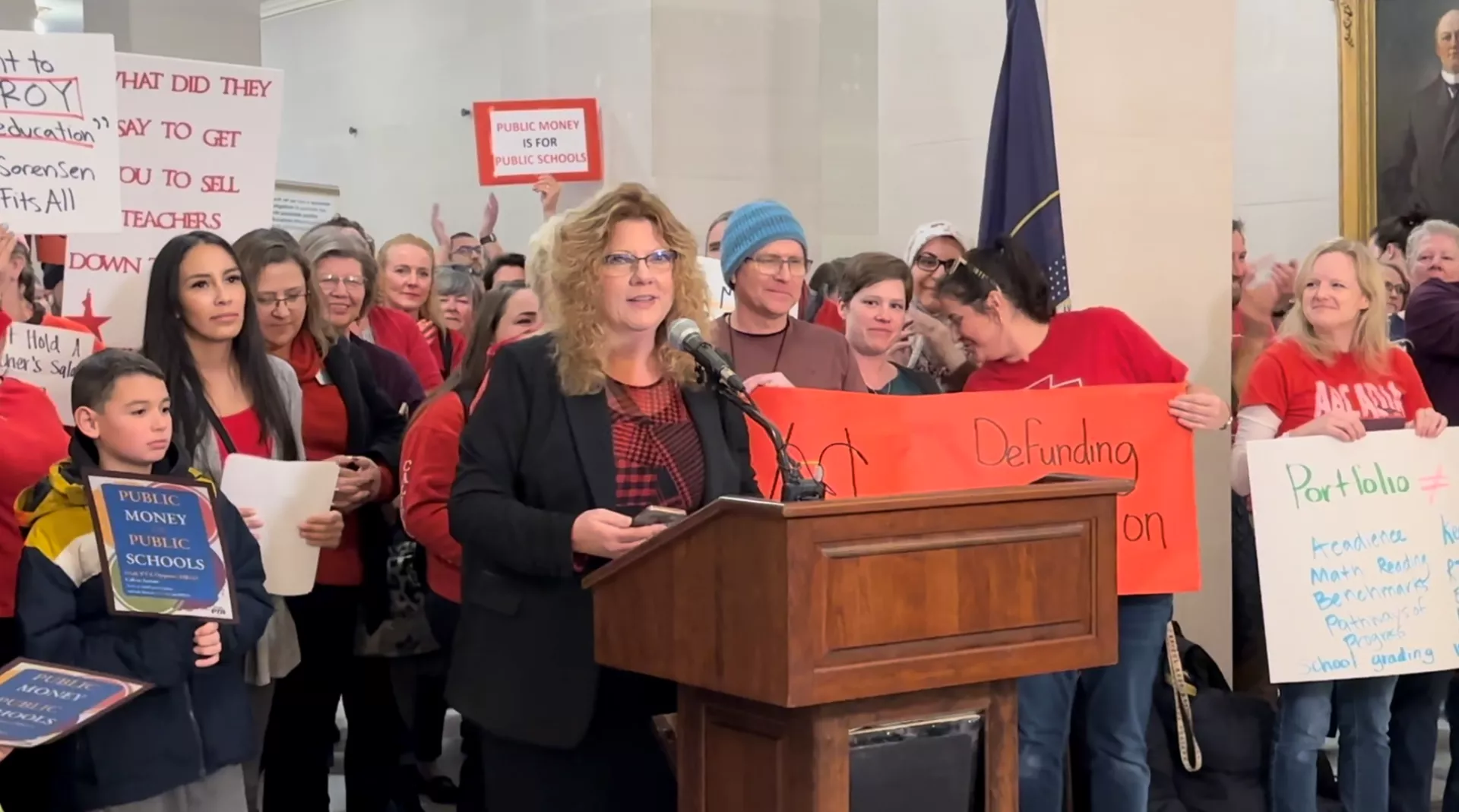 UEA President Renée Pinkney at a podium speaking at a rally.