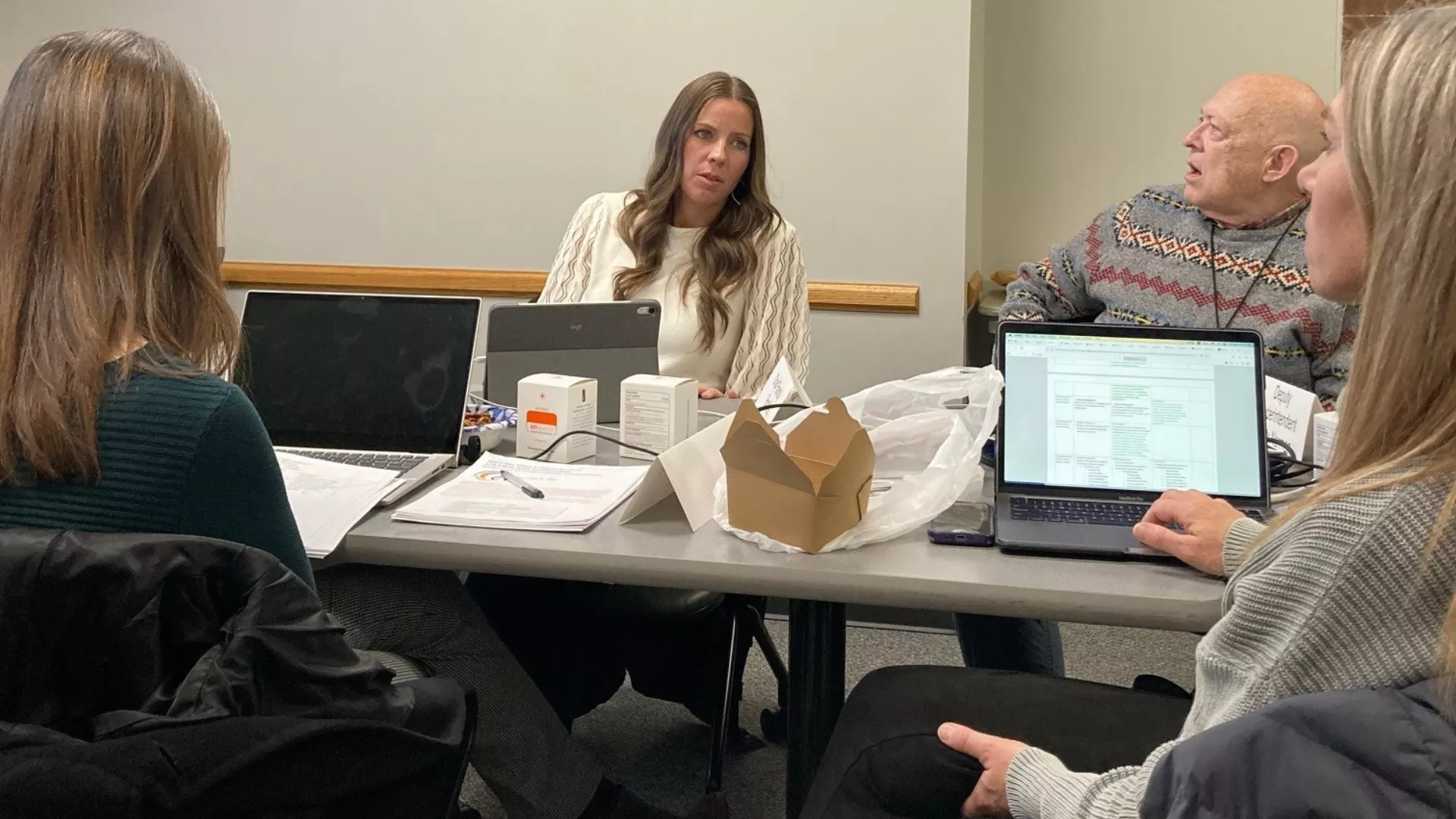 Four Utah State Board of Education members sit around table and talk.