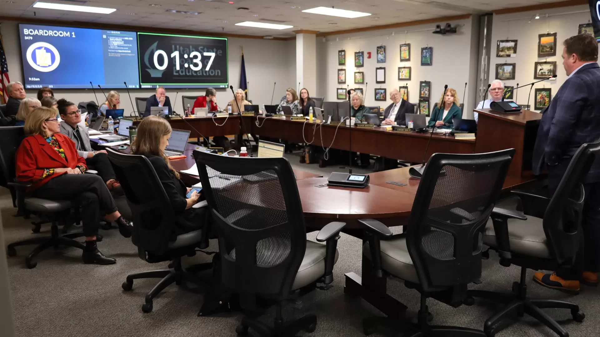 Utah State Board of Education members sit around a large circled table with a hole in it and listen to public comment. 