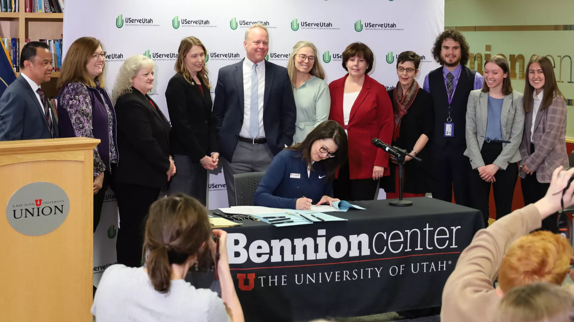 Lt. Governor Deidre Henderson signs a law with a group of people standing behind her.
