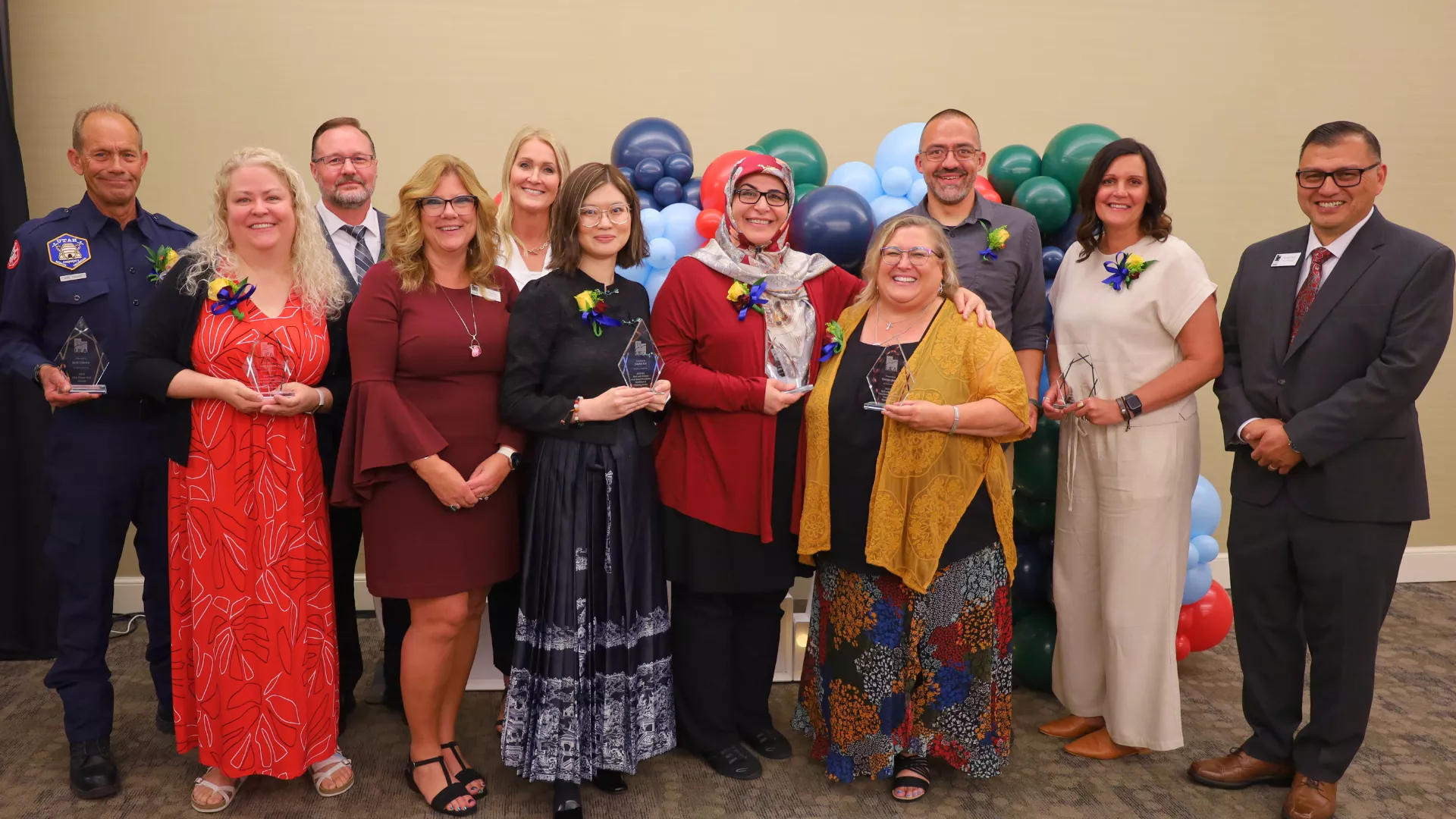Group of 11 award winners holding trophies with UEA leadership.