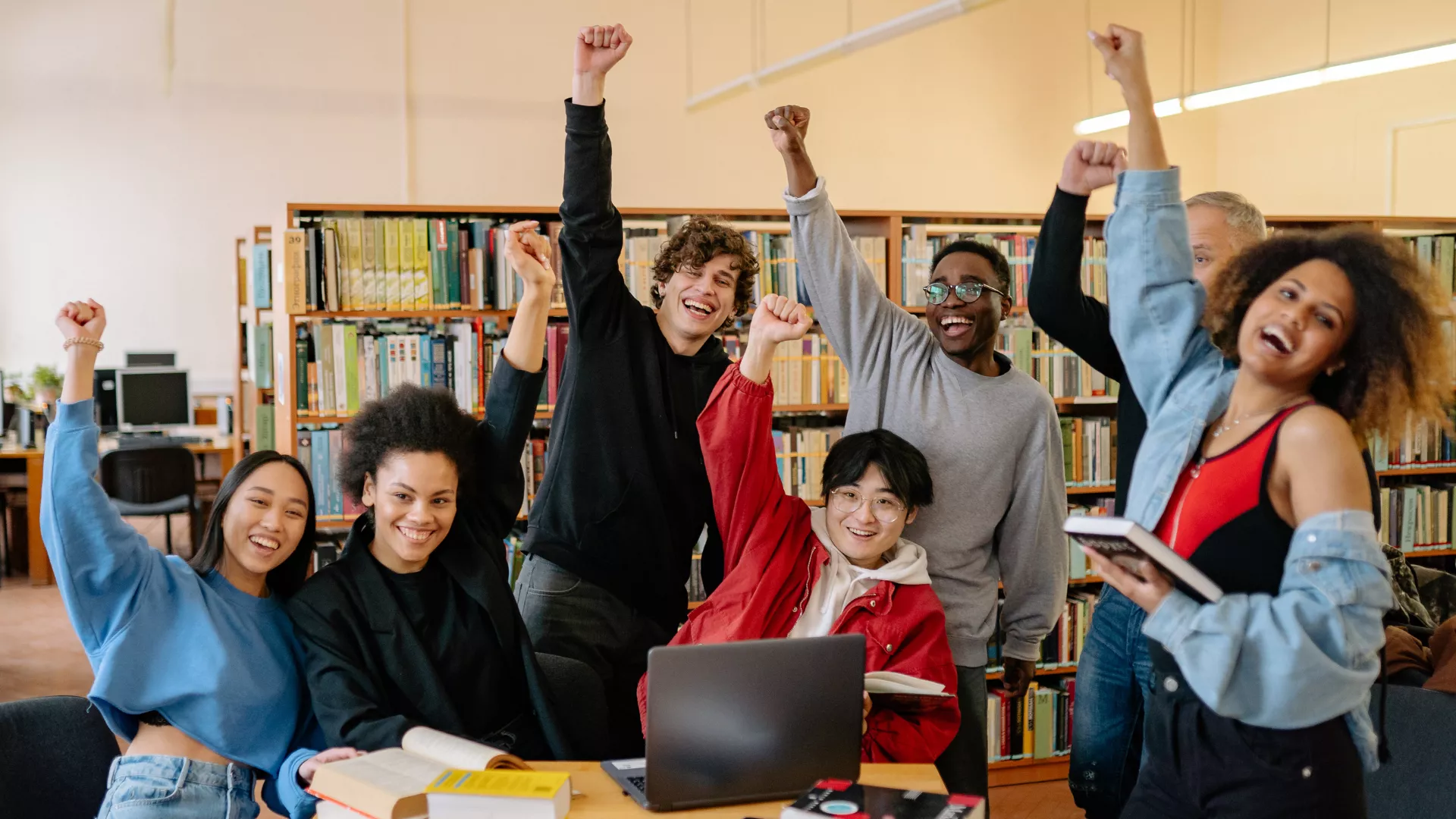 Six college students smile and put up their fists.
