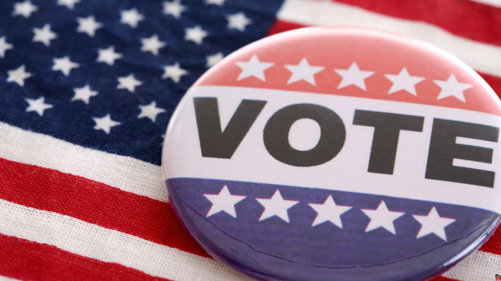 Vote pin with american flag in the back.