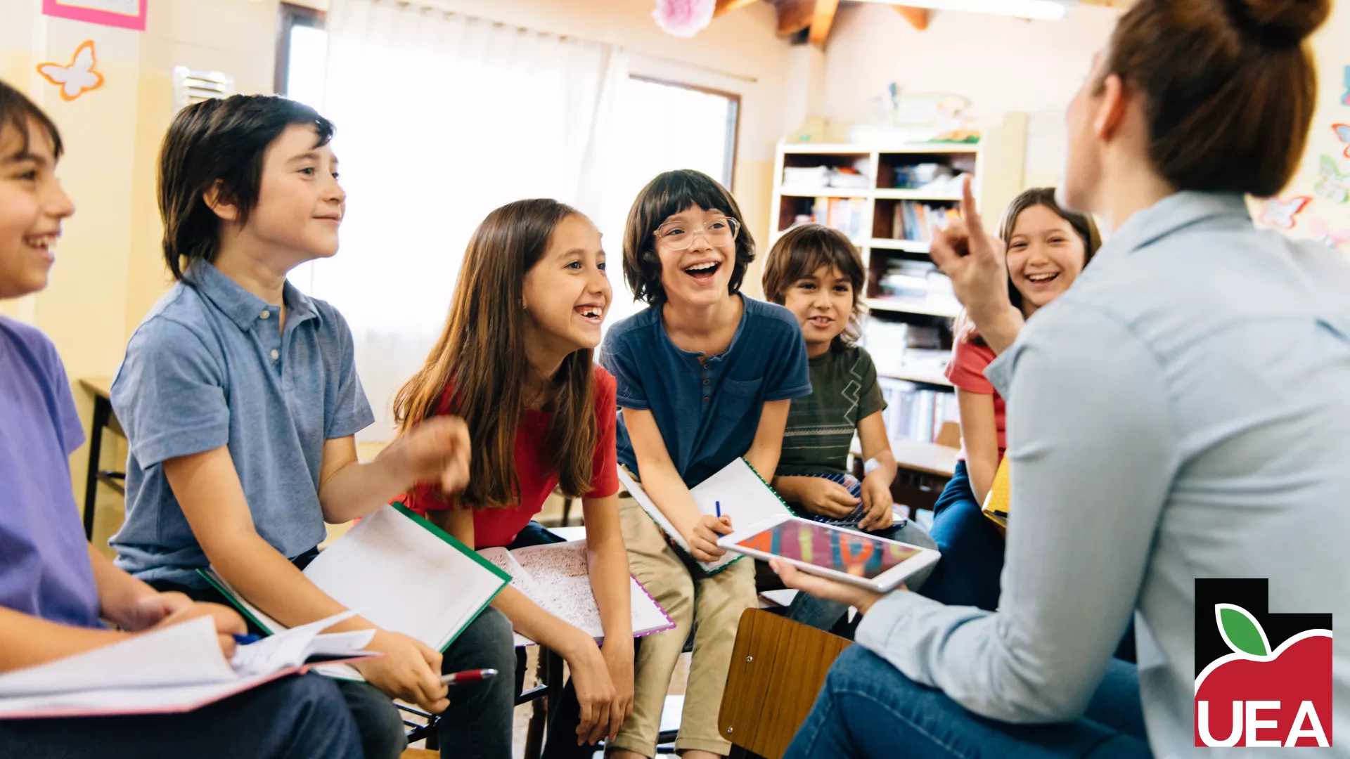 Six middle-school aged students smile at teacher. 