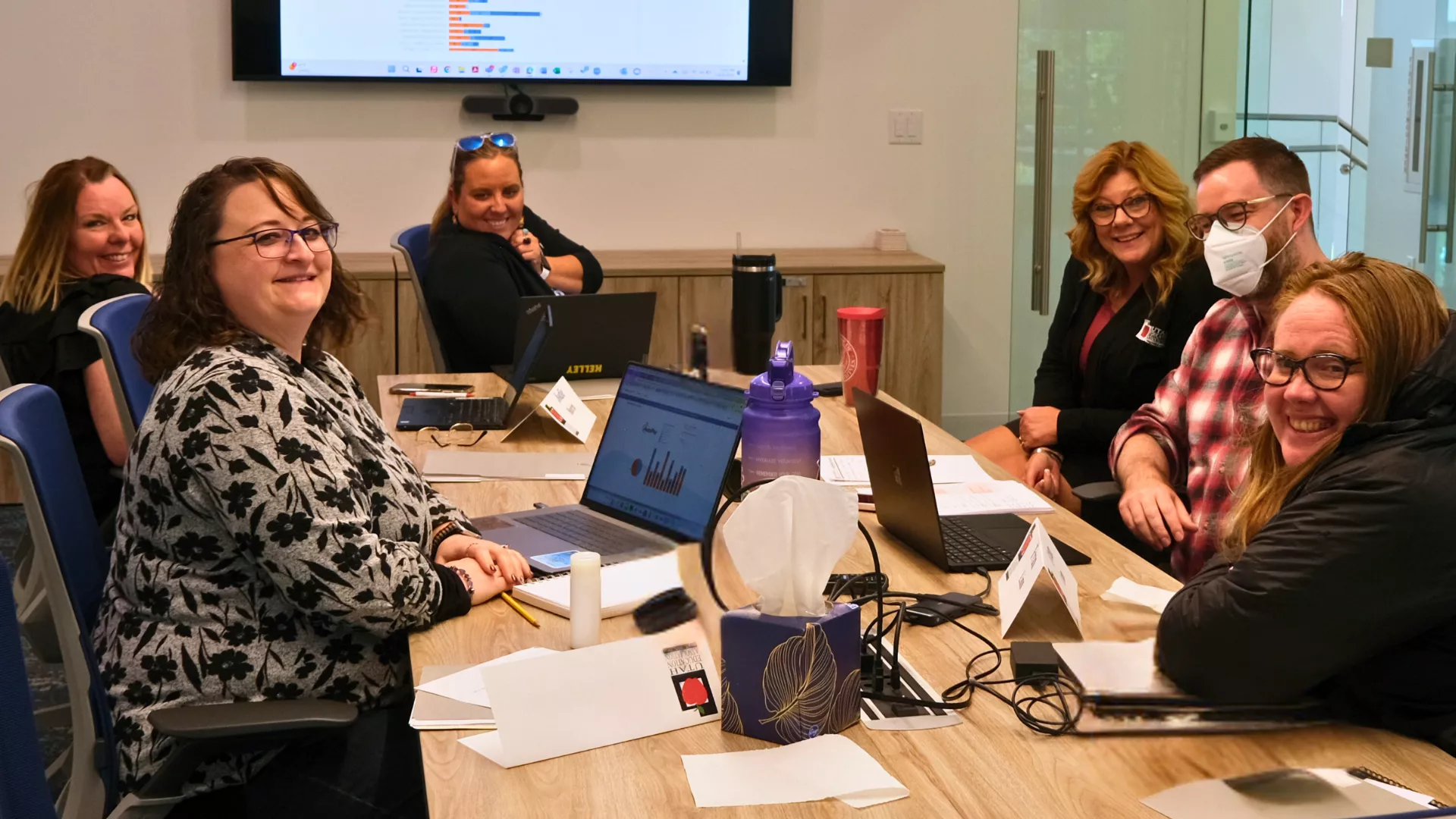 Six people sit around a table smiling.