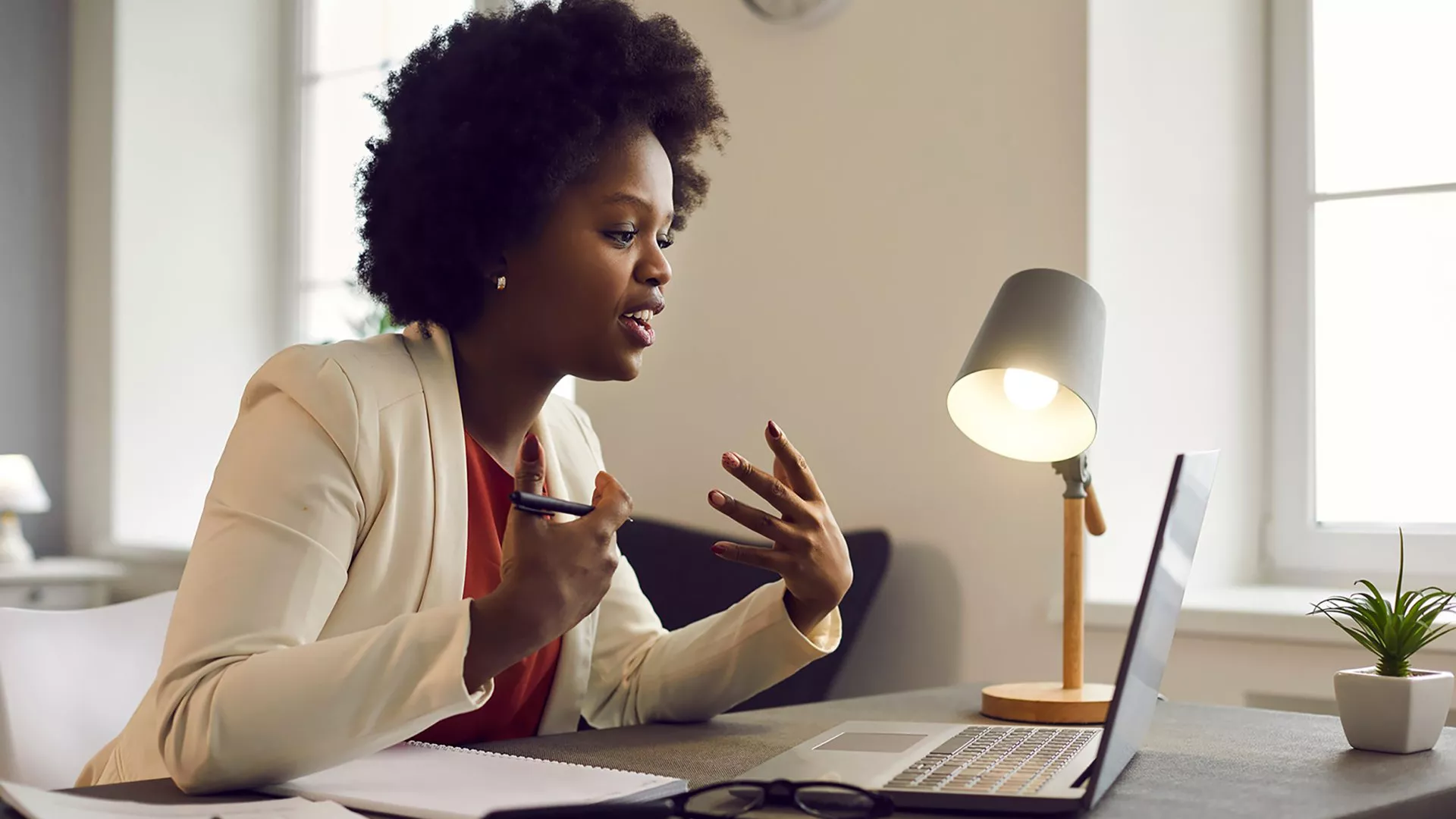 Black professional woman sits at a desk and participates in an online meeting