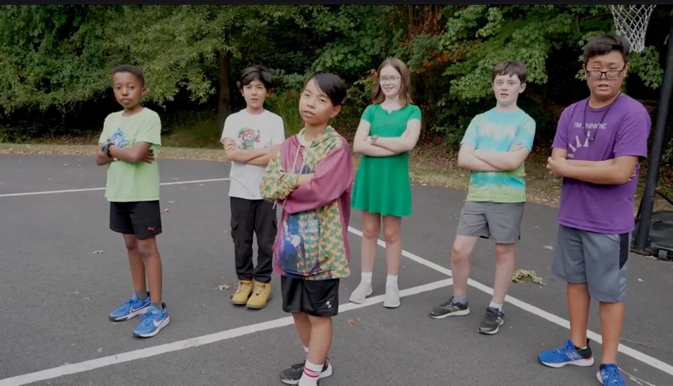 six middle school students stand outside with arms folded