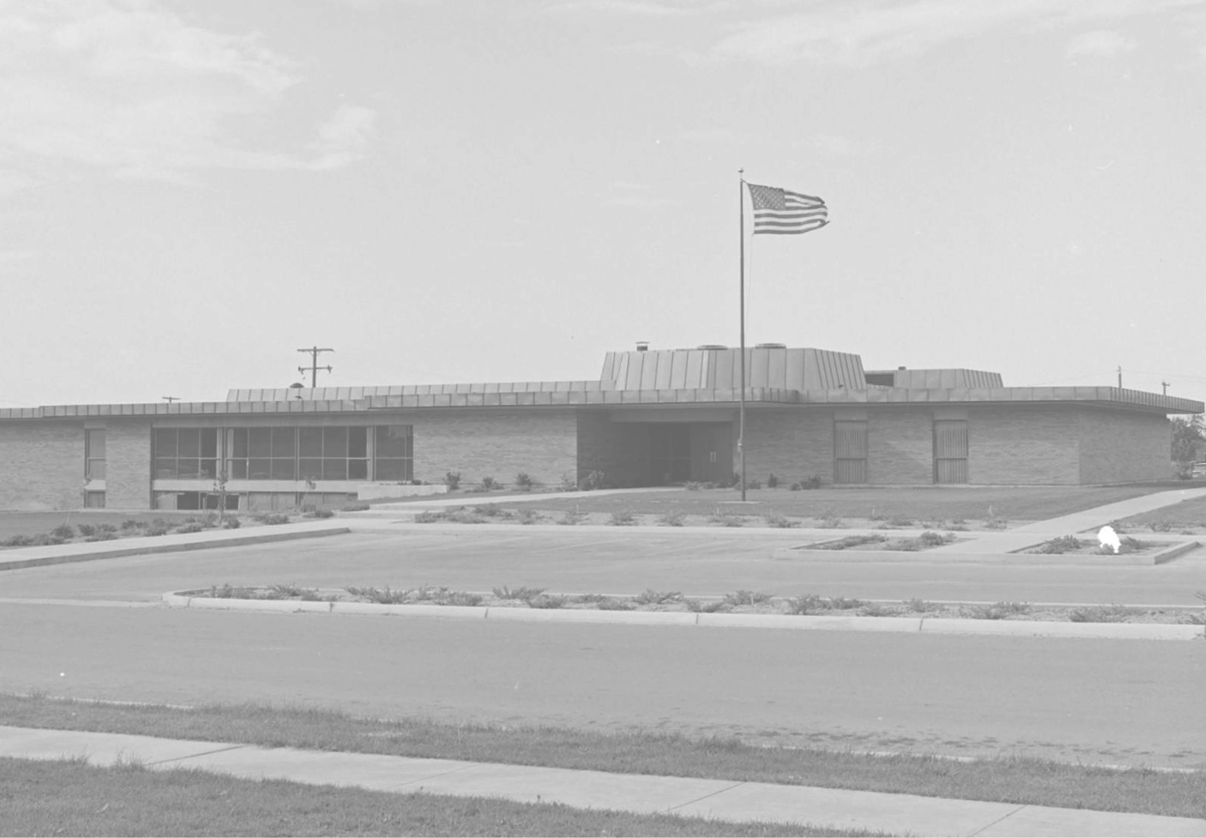 A municipal building with the American flag flying at full staff in the foreground