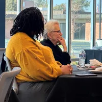 Two women sit at table.