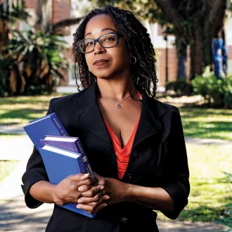 Niseiki McFerren stands outside carrying textbooks