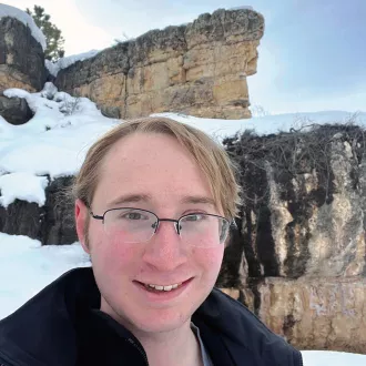 headshot of Ryan Grozen with a snow-covered cliff in the background