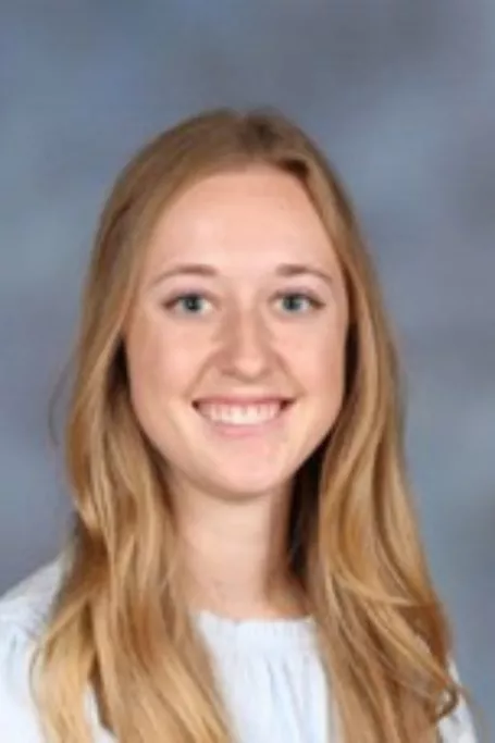 School picture of a white woman with blonde hair with a grey background.