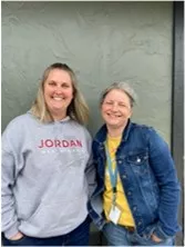 Two women against a grey background smiling.
