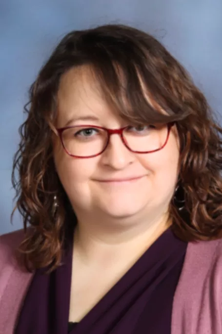 White woman with brown hair and glasses.