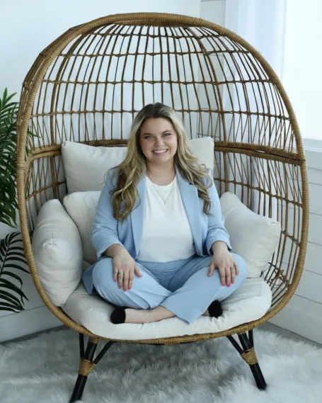 Woman in blue suit sits in chair. 