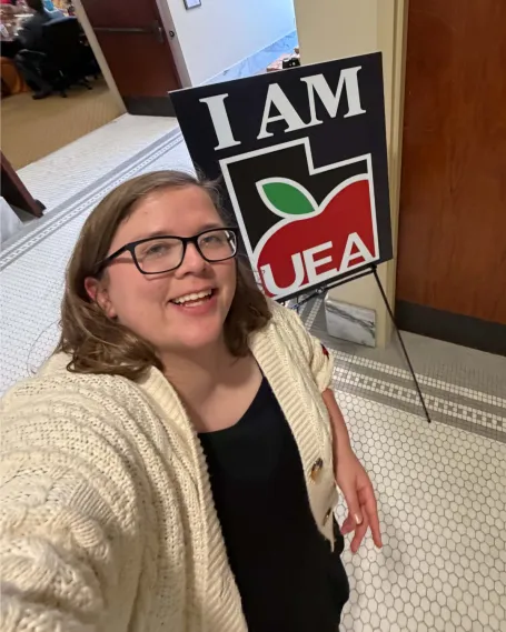 Woman smiling in front of sign.