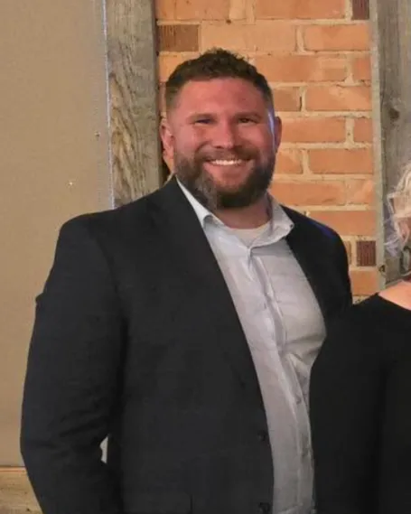 Greg Burrow in suit jacket smiling. 
