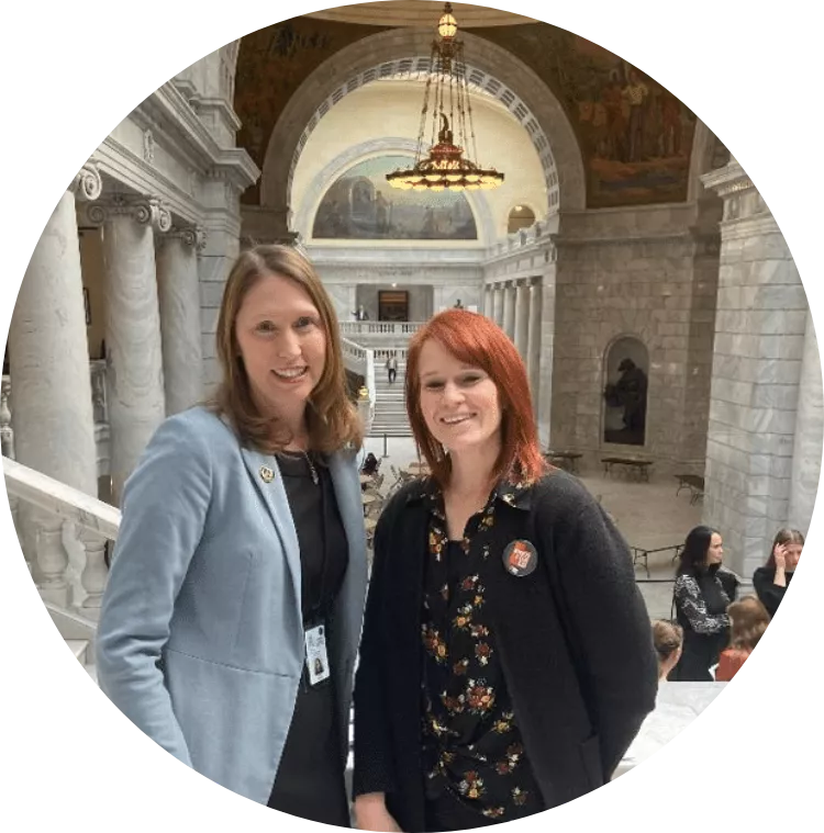 Two women wearing jackets smiling in the Utah State Capitol rotunda.
