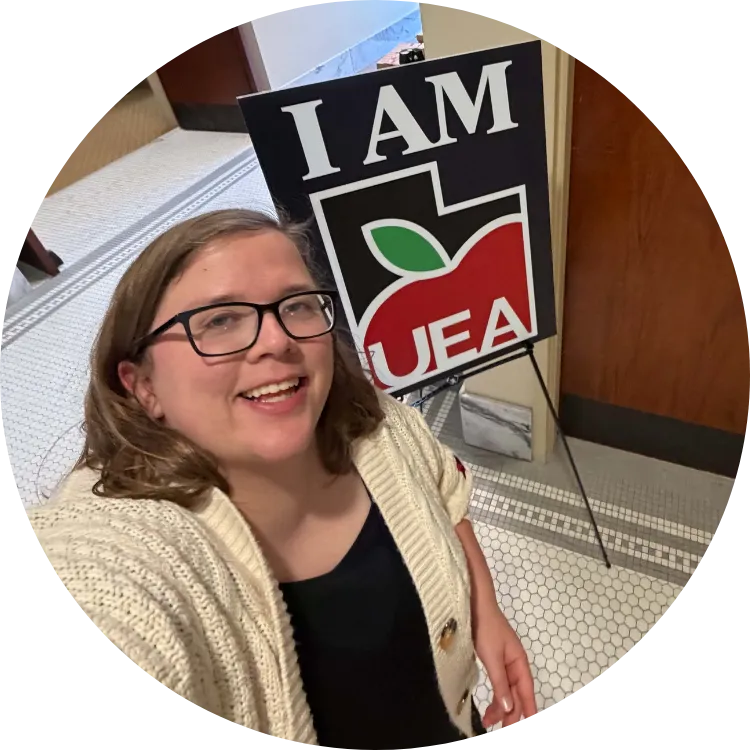 Woman smiles next to a UEA sign.