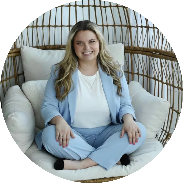 Woman in blue suit smiles in chair. 