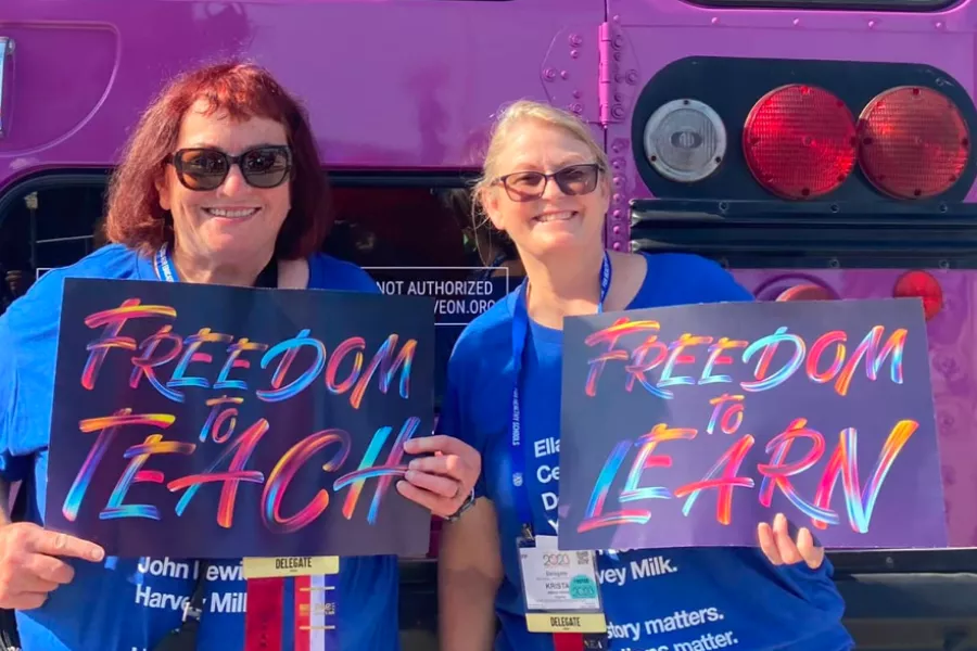 Members pose with "Freedom to Teach" and "Freedom to Learn" signs.