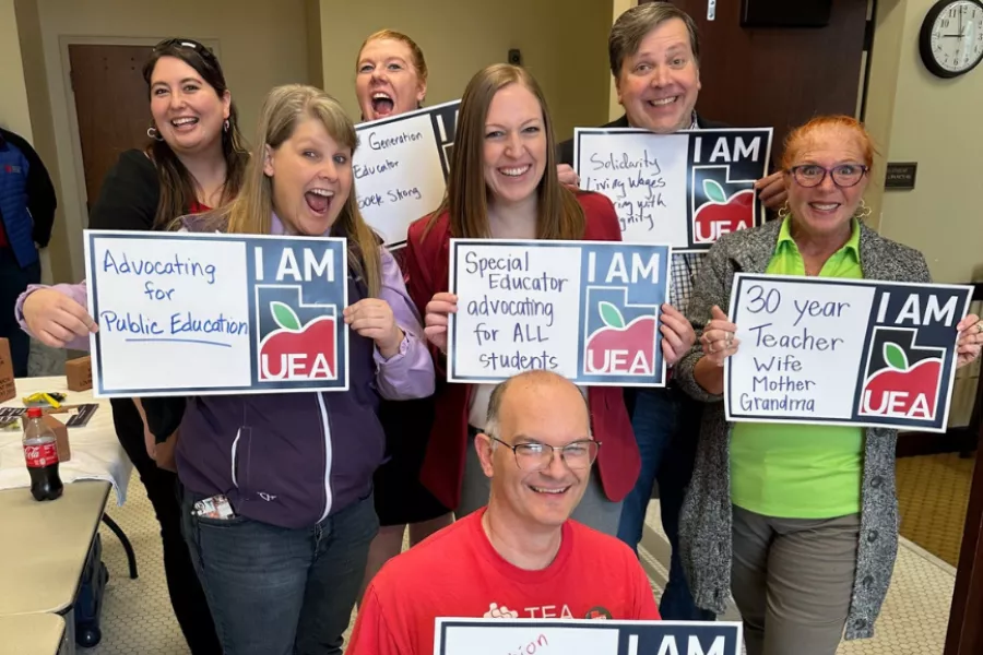 Seven people hold up signs that read: I am UEA.